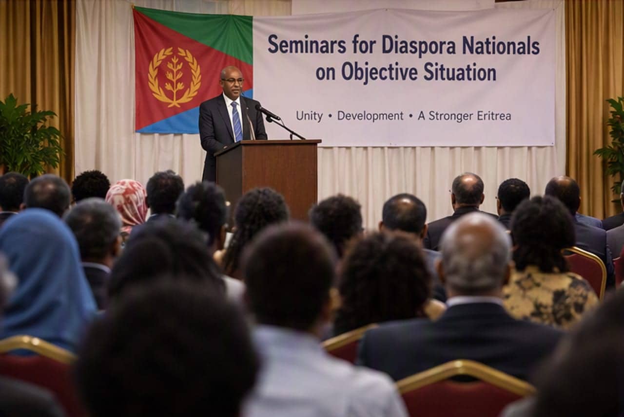 ንድፊ ናይ ሓደ ኤርትራዊ ዲፕሎማሲያዊ ኣብ ቅድሚ ባንዴራ ኤርትራን "Seminars for Diaspora Nationals on Objective Situation" ዝብል ሰሌዳን ኣብ መድረኽ እናተዛረበ፡ ንዝተቐመጡ ተሳተፍቲ ገጹ ኣቕኒዑ
